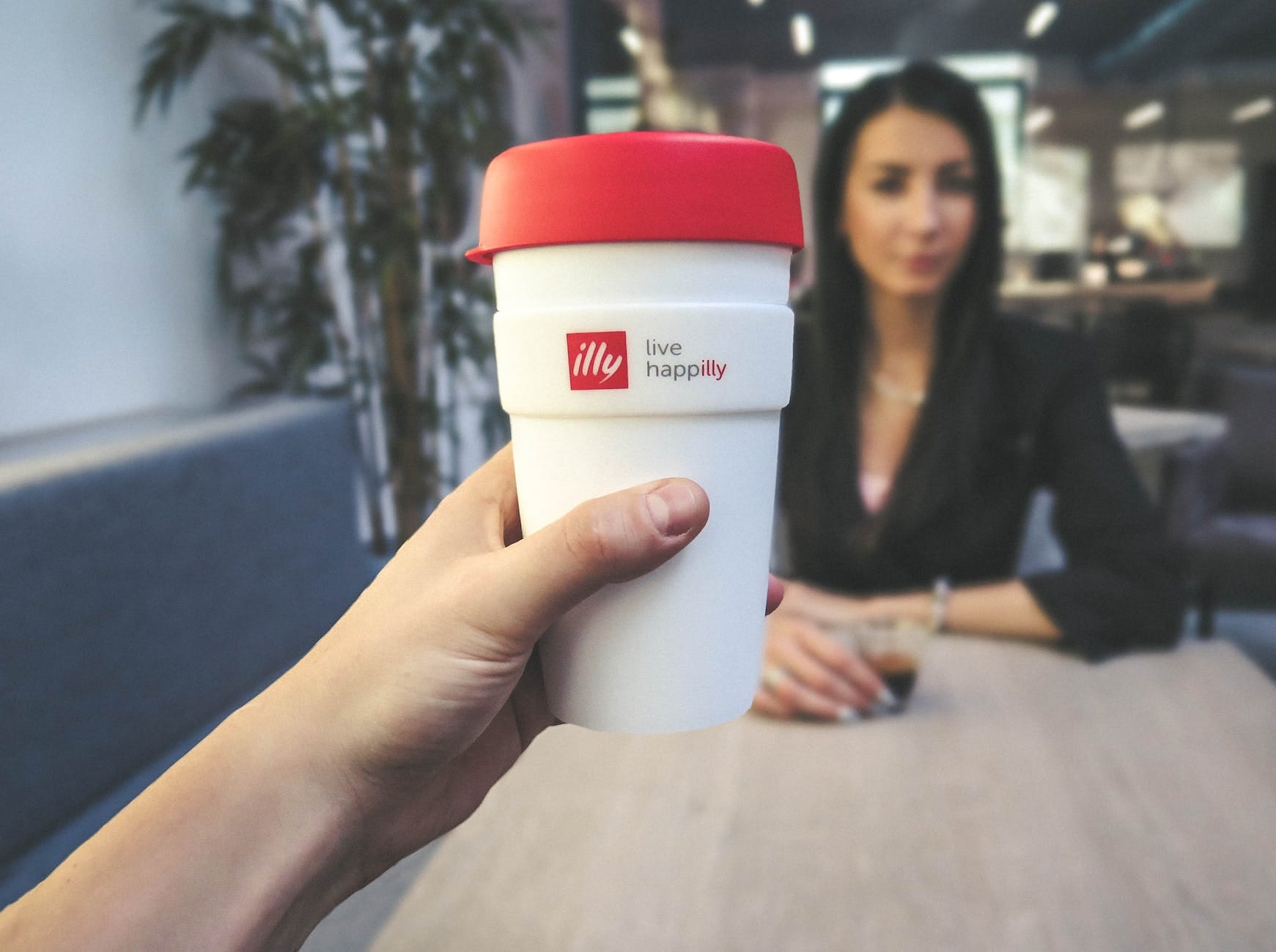 person holding white and red live happilly cup